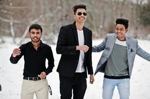 grupp av tre casual unga indiska män poserade på vinterdagen ha kul och dansa. foto