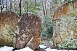 uråldriga stora stenar med gravyr vid grön skog med lite snötäcke i Karpaterna. foto