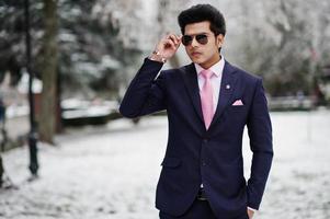 elegant indisk macho man modell på kostym och rosa slips, solglasögon poserade på vinterdagen. foto
