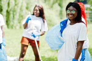 grupp glada afrikanska volontärer med soppåsar rengöringsområde i parken. Afrika volontärarbete, välgörenhet, människor och ekologi koncept. foto