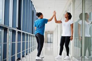 två afrikanska kvinnliga vänner i t-shirts ger varandra high five inomhus tillsammans. foto