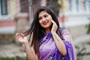 närbild porträtt av indisk hinduisk flicka på traditionella violetta saree poserade på gatan. foto