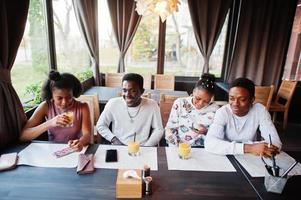 glada afrikanska vänner sitter och chattar på café. grupp av svarta folk som möter och dricker juice i restaurangen. foto