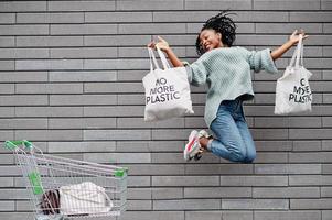 ingen mer plast. afrikansk kvinna med kundvagnsvagn och ekopåsar hoppa utomhusmarknad. foto