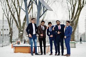 grupp av fem indisk affärsman i kostymer poserade utomhus i vinterdag i Europa mot solpaneler. foto