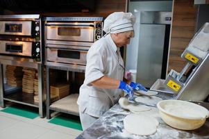 kvinnlig kock förbereder pizza i restaurangkök. foto