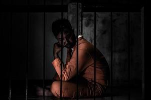 asiatisk man desperat vid järnfängelset, fångkoncept, thailändskt folk, hoppas att bli fri, seriösa fångar fängslade i fängelset foto
