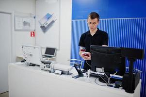 säljare man mobiltelefon professionell konsult i teknisk butik eller butik arbetar i kassan. foto