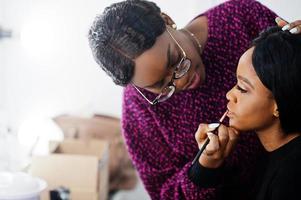 afrikansk amerikansk kvinna som sminkar sig av make-up artist på skönhetssalongen. foto