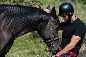 arabiska högt skägg man bär i svart hjälm med arabisk häst. foto
