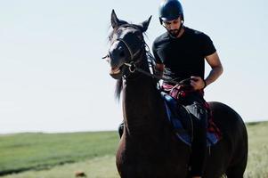 arabiska högt skägg man bär i svart hjälm, rida arabisk häst. foto