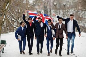 grupp av sex indisk affärsman i kostymer poserade utomhus på vinterdagen i Europa med Storbritanniens flagga. vänskapliga förbindelser med Indien och Storbritannien. foto