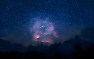 Vintergatan och rosa ljus vid bergen. natt färgglada landskap. stjärnhimmel med kullar på sommaren. vackert universum. rymdbakgrund med galax. resor bakgrund foto