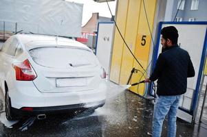 sydasiatisk man eller indisk man som tvättar sin vita transport på biltvätt. foto