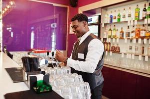 afroamerikansk bartender i baren häller från kranen färsk öl i glaset i puben. foto