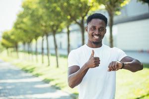 en ung afroamerikansk man, på en morgonjoggingtur i en vit t-shirt i parken, nöjd foto