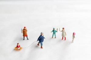 miniatyr människor lycklig familj rida en släde med snö bakgrund foto