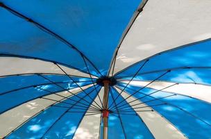 metallramen inuti det stora tvåfärgade paraplyet nära stranden. foto