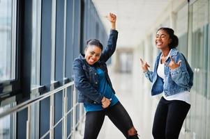 två afrikansk kvinna vänner i jeans jacka visa rock fingrar inomhus tillsammans. foto