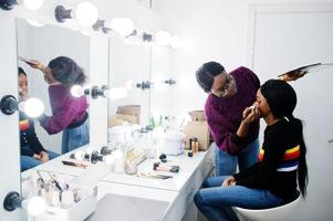 afrikansk amerikansk kvinna som sminkar sig av make-up artist på skönhetssalongen. foto