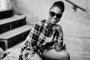 hip hop afrikansk amerikansk tjej på solglasögon och jeansshorts. casual street fashion porträtt av svart kvinna. foto