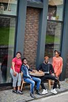 fyra afrikanska vänner sitter vid bordet i utomhuscafé. två svarta tjejer med killar. foto