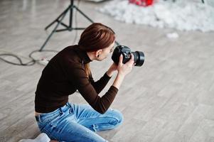 ung flicka fotograf fotografering på studio. professionell fotograf på jobbet. foto