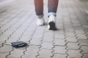 man letar efter plånbok som ligger på trottoaren foto