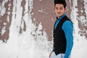casual ung indisk man i blå skjorta och svart väst poserade på vinterdagen. foto