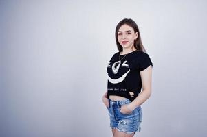 porträtt av en attraktiv tjej i svart t-shirt som säger lol och jeansshorts poserar i studion. foto