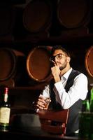stilig välklädd arabisk man med ett glas whisky och cigarr poserade på puben. foto