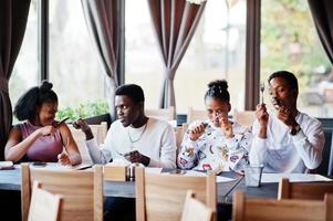 glada afrikanska vänner sitter och chattar på café. grupp av svarta folk som möts i restaurangen och har roligt tillsammans. foto