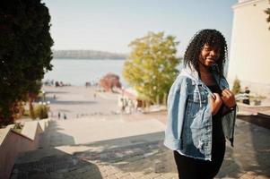 snygg trendig afro frankrike lockig kvinna poserade på höstdagen i jeansjacka. svart afrikansk kvinnlig modell. foto