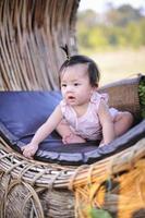 porträtt sött spädbarn barn småbarn sitter i rosa klänning, närbild asiatisk flicka med lycka av 8 månader gammal foto