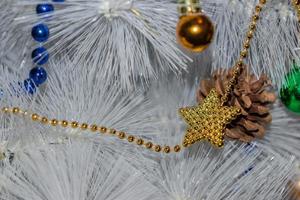 helgdagar, nyår och firande koncept - vit julgran. gyllene och blå girlang, kotte, gröna och gyllene kulor foto
