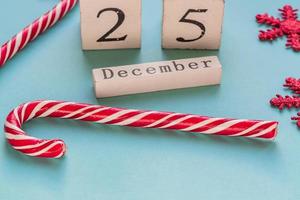 träblockskalender som visar 25 december. jullov. gratulationskort med godisrör och gnistrande snöflingor. foto