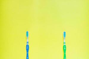 två tandborstar på gul bakgrund. ovanifrån, minimal platt läggning. foto