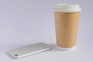 hantverkspapper kaffekopp och metallisk smartphone på grå bakgrund i minimalistisk stil foto