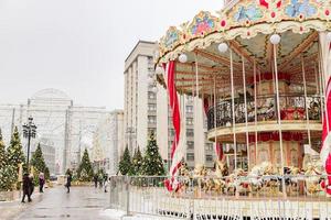 Moskva, Ryssland, 2018 - juldekorerade träd och färgglad karusell på manezhnaya-torget i en snöig dag. foto