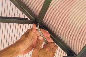 manliga händer som håller hylsnyckel fixerande tak av polykarbonat foto