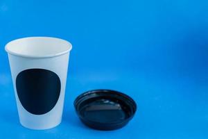 närbild av vitt papper kraft engångskopp för kaffe med svart plastlock på blå bakgrund med kopia utrymme foto