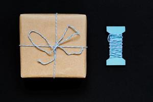 handgjord presentförpackning inslagen i hantverkspapper med blått band och rosett foto
