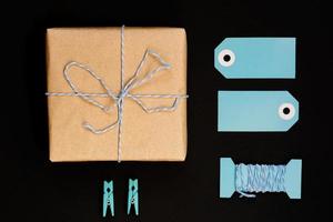 handgjorda presentförpackningar inslagna i hantverkspapper med blå papperskortetikett, rep och klädnypor av trä för dekoration. foto