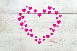 stort rosa hjärta av utskuret papper små hjärtan på träbakgrund. handgjord dekoration för alla hjärtans dag. foto