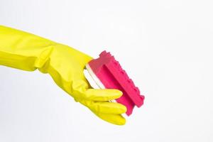 hand med gul handske som håller röd svamp för rengöring på vit bakgrund foto