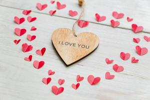 stort rött hjärta gjort av utklippt papper små hjärtan och trähjärta med jag älskar dig-inskription på träbakgrund. handgjord dekoration för alla hjärtans dag. foto