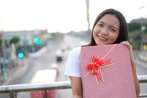 Lycklig ung flicka med gåva låda. foto