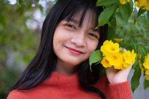 porträtt ung flicka med gula blommor, asiatisk flicka. foto