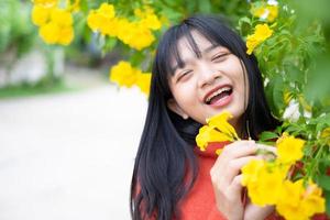 porträtt ung flicka med gula blommor, asiatisk flicka. foto