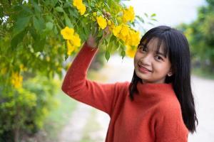 porträtt ung flicka med gula blommor, asiatisk flicka. foto